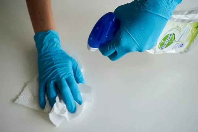 Handen van een persoon die een oppervlak schoonmaakt.