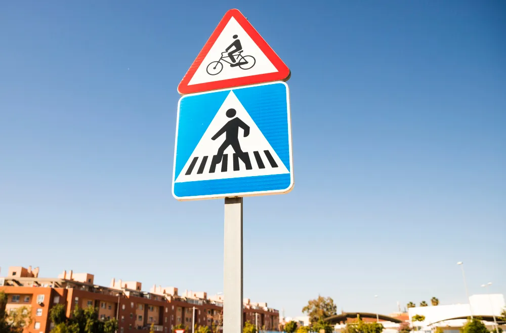Panneau d'avertissement de vélo triangulaire au-dessus du panneau de signalisation de passage piéton carré dans la ville