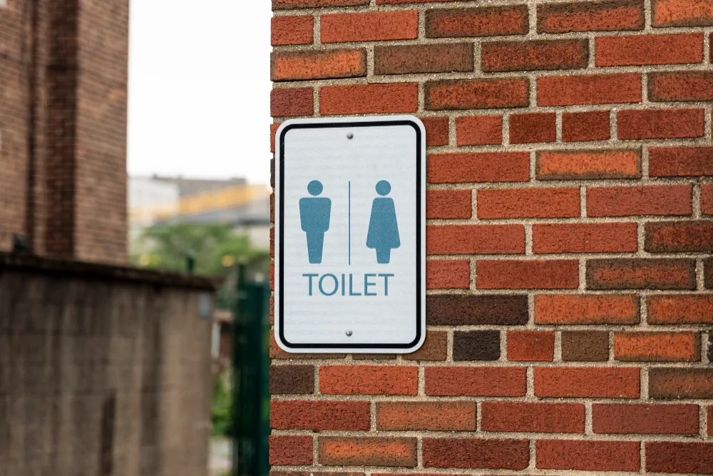 Panneau signalétique de toilettes publiques pour hommes et femmes sur un mur en briques