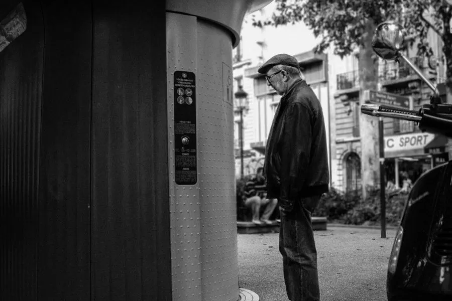 Homme attendant l'ouverture automatique d'un sanitaire public