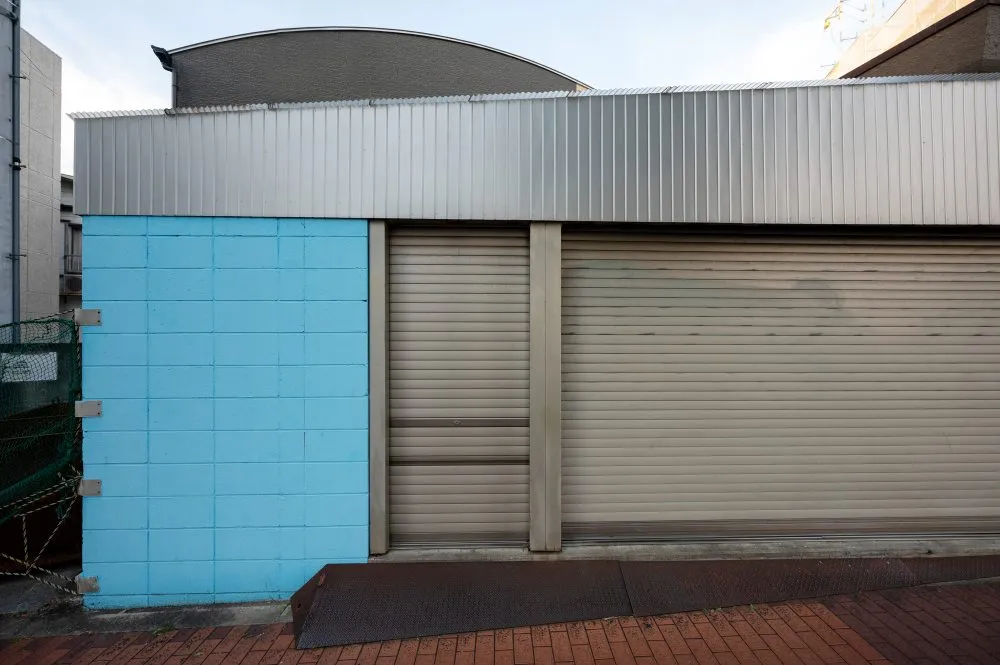 Conteneurs avec façade industrielle avec mur en parpaings bleus et grande porte métallique fermée