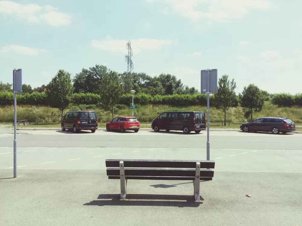 Lege bank naast auto's op een parkeerplaats met de lucht op de achtergrond