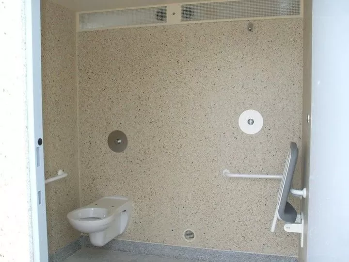 Intérieur d'une cabine sanitaire avec toilettes et aide PMR