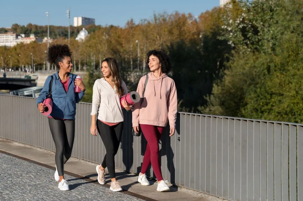 Une groupe de personnes marche en milieu urbain avec des accessoires de sport à la main.