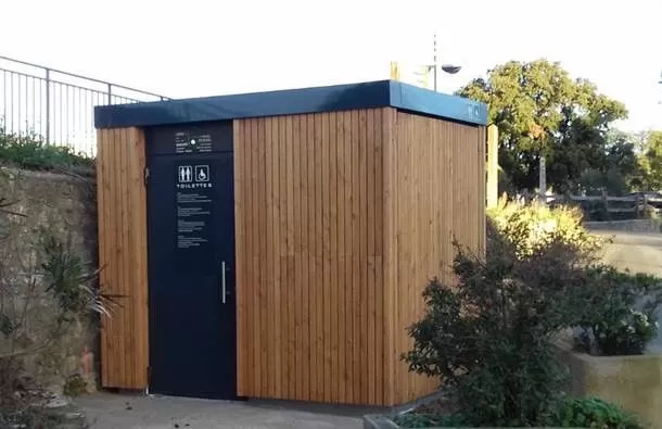 Sanitaires publics façade en bois entouré de buissons