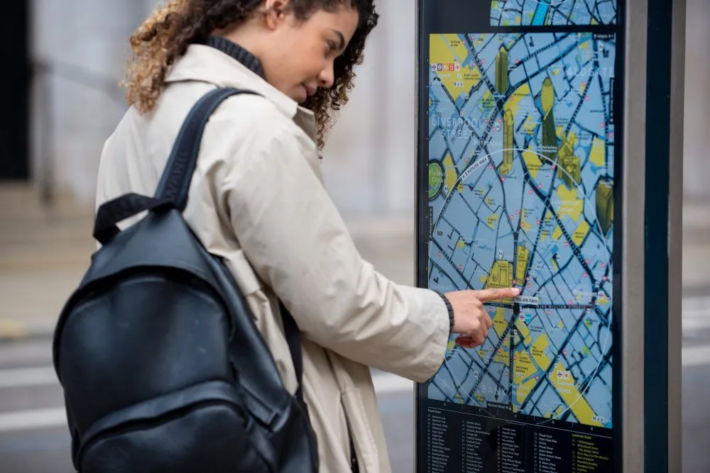 Femme consultant un plan sur un panneau d’information urbain